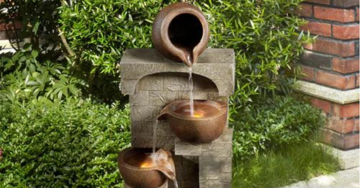 A solar-powered water fountain set amongst landscaping adding decor to an outdoor living space.